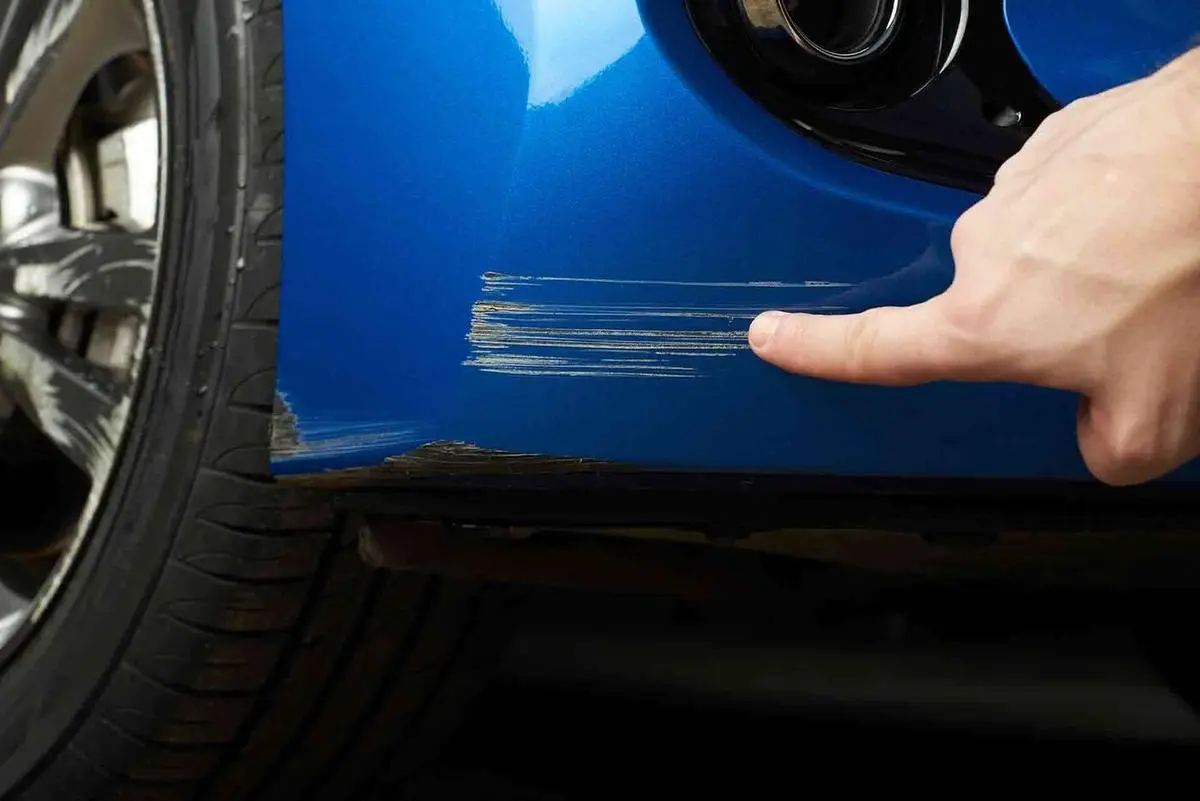 Technician repairing a deep scratch in car paintwork