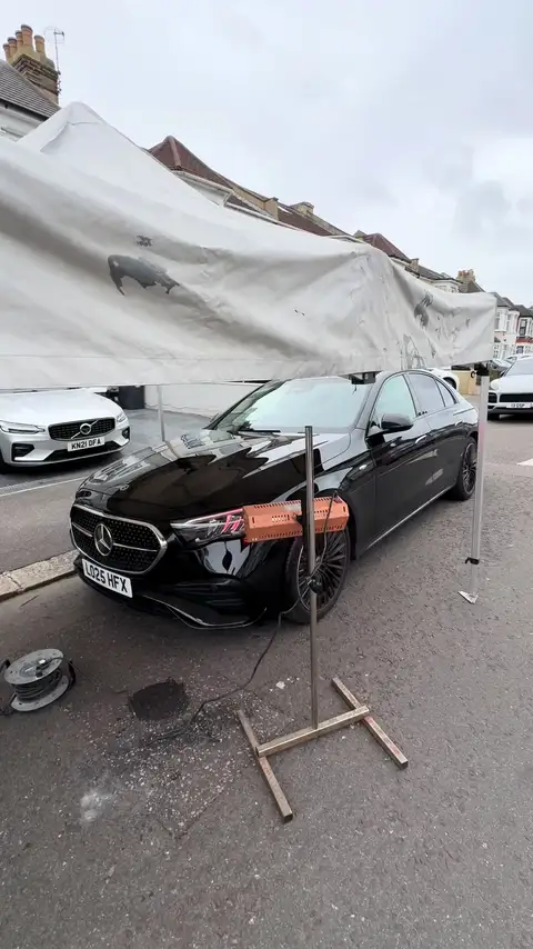 Mercedes saloon under a mobile spray shelter on a residential London street